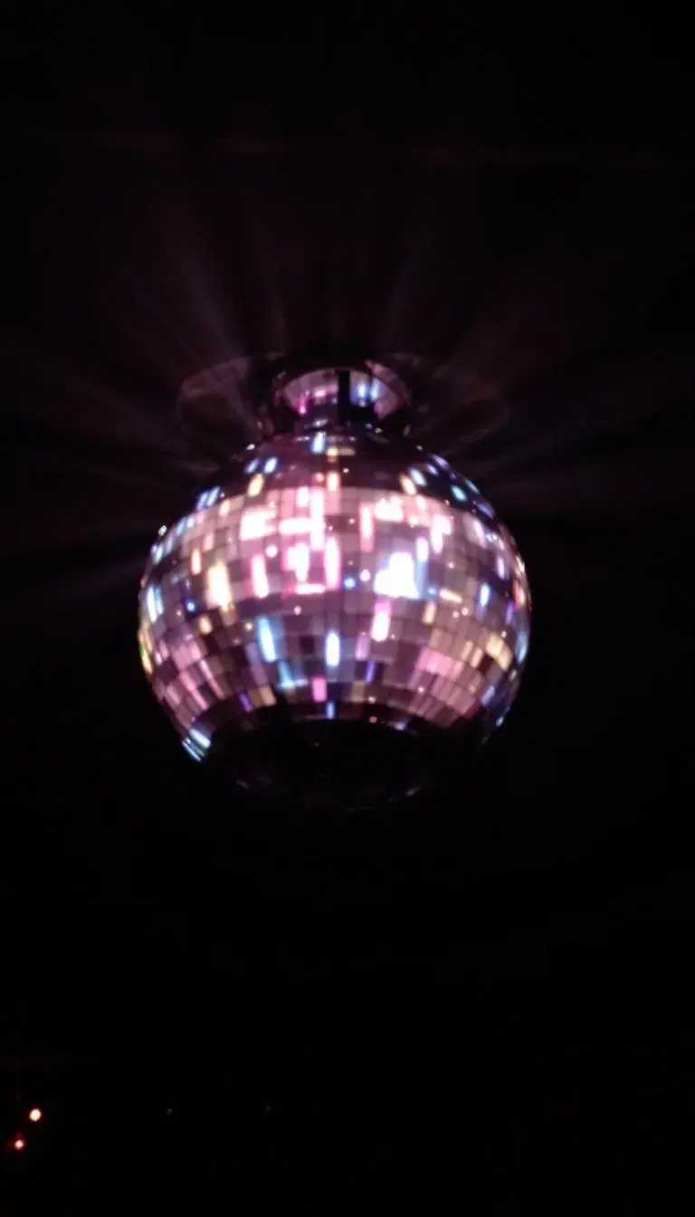 A large, glossy black disco ball with a mesmerizing light show, casting a dramatic shadow on the surrounding area.